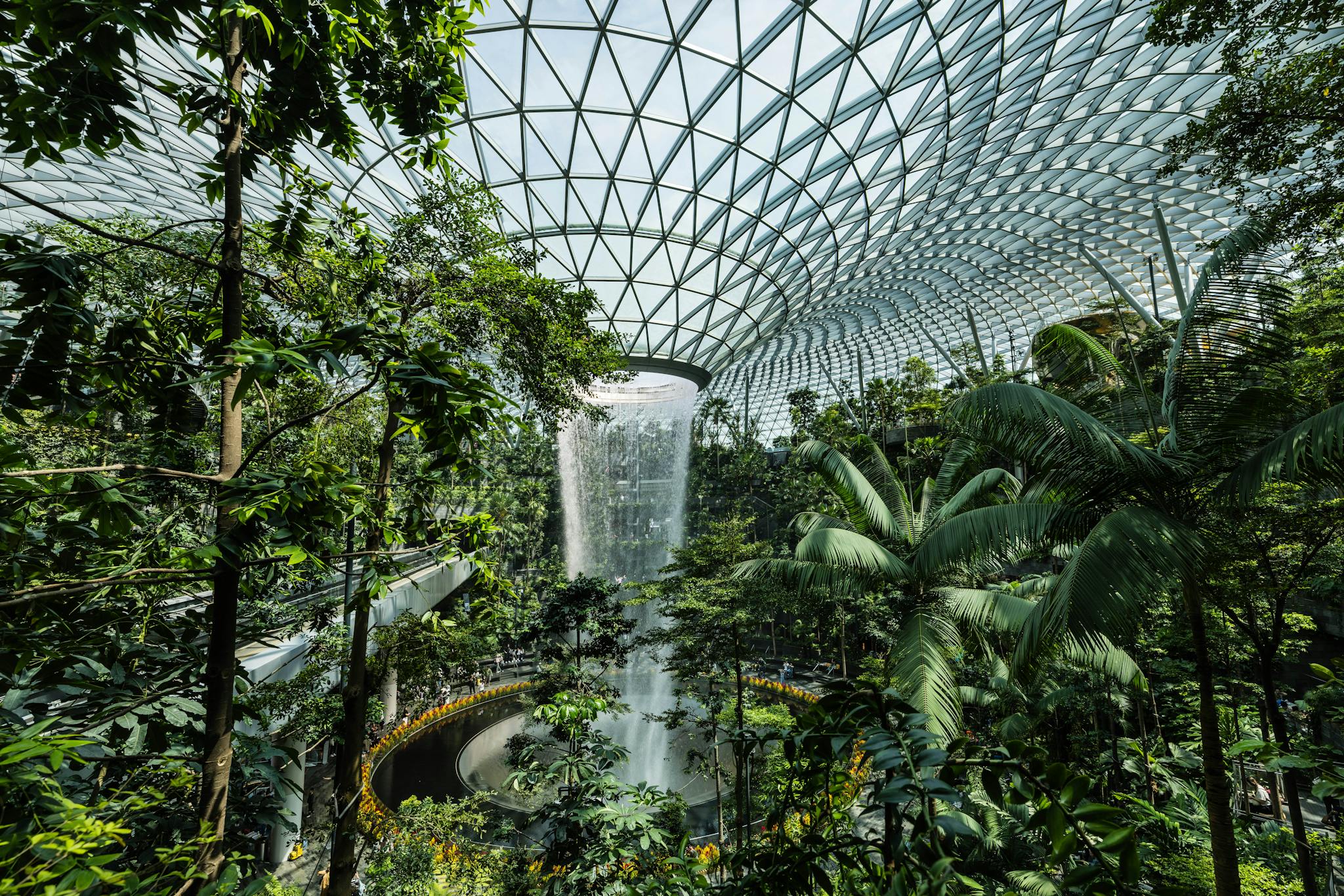 Magnificent indoor waterfall surrounded by tropical greenery inside Jewel Changi Airport, Singapore.